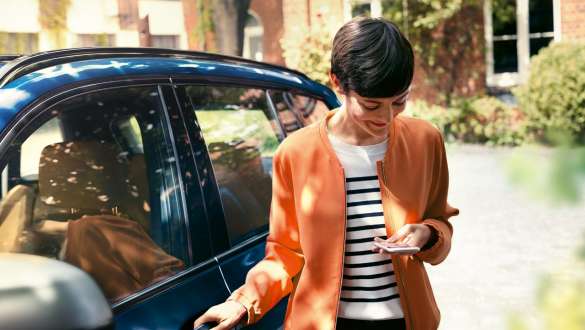 Femme avec vue sur son smartphone, BMW Série 5 Berline G30 Femme descend de la BMW avec vue sur son smartphone, BMW Série 5 Berline G30
