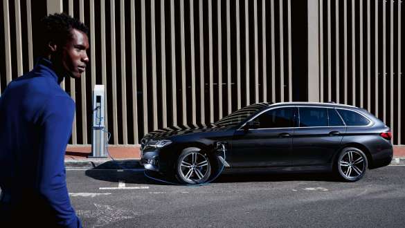 BMW Série 5 Touring 2021 G31 hybride rechargeable, vue de profil, branchée à une borne de recharge BMW Série 5 Touring 2021 G31 hybride rechargeable, vue de profil, branchée à une borne de recharge avec modèle