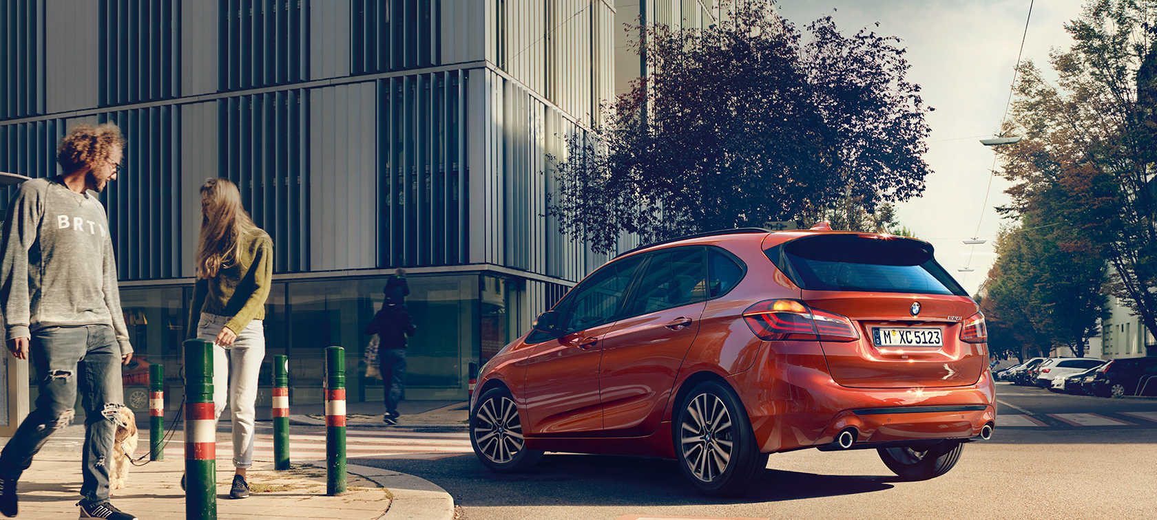 Vue de trois quarts arrière de la BMW Série 2 Active Tourer 220i BMW Série 2 Active Tourer 220i F45 restylage 2018 Sunset Orange metallic, vue de trois quarts de profil, en mouvement sur la route