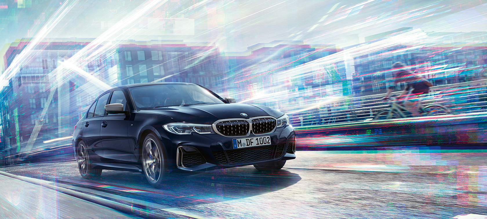 BMW Série 3 Berline, modèle M340i xDrive. Vue latérale de trois-quarts BMW M340i xDrive roulant dans un décor urbain.