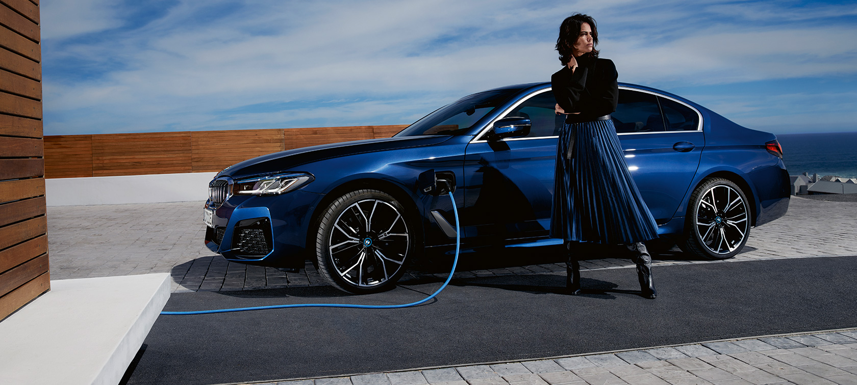 BMW Série 5 Berline hybride rechargeable 2021 G30 vue de profil branchée à une borne de recharge BMW Série 5 Berline hybride rechargeable 2021 G30, vue de profil branchée à une borne de recharge avec modèle