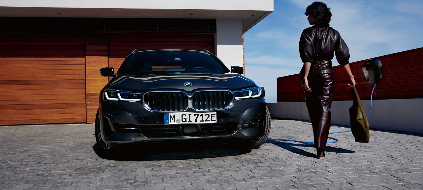 BMW 5er Touring 2021 G31 hybride rechargeable, vue avant, branchée à une borne de recharge BMW Série 5 Touring 2021 G31 hybride rechargeable, vue avant, branchée à une borne de recharge avec modèle