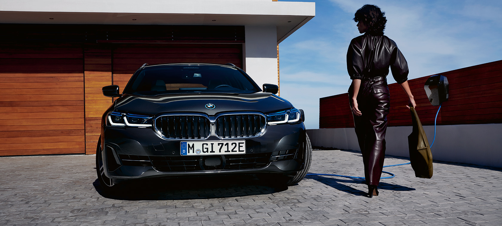 BMW hybride rechargeable Série 5 Touring 2021 G31 LCI branchée à une borne de recharge, vue avant avec mannequin