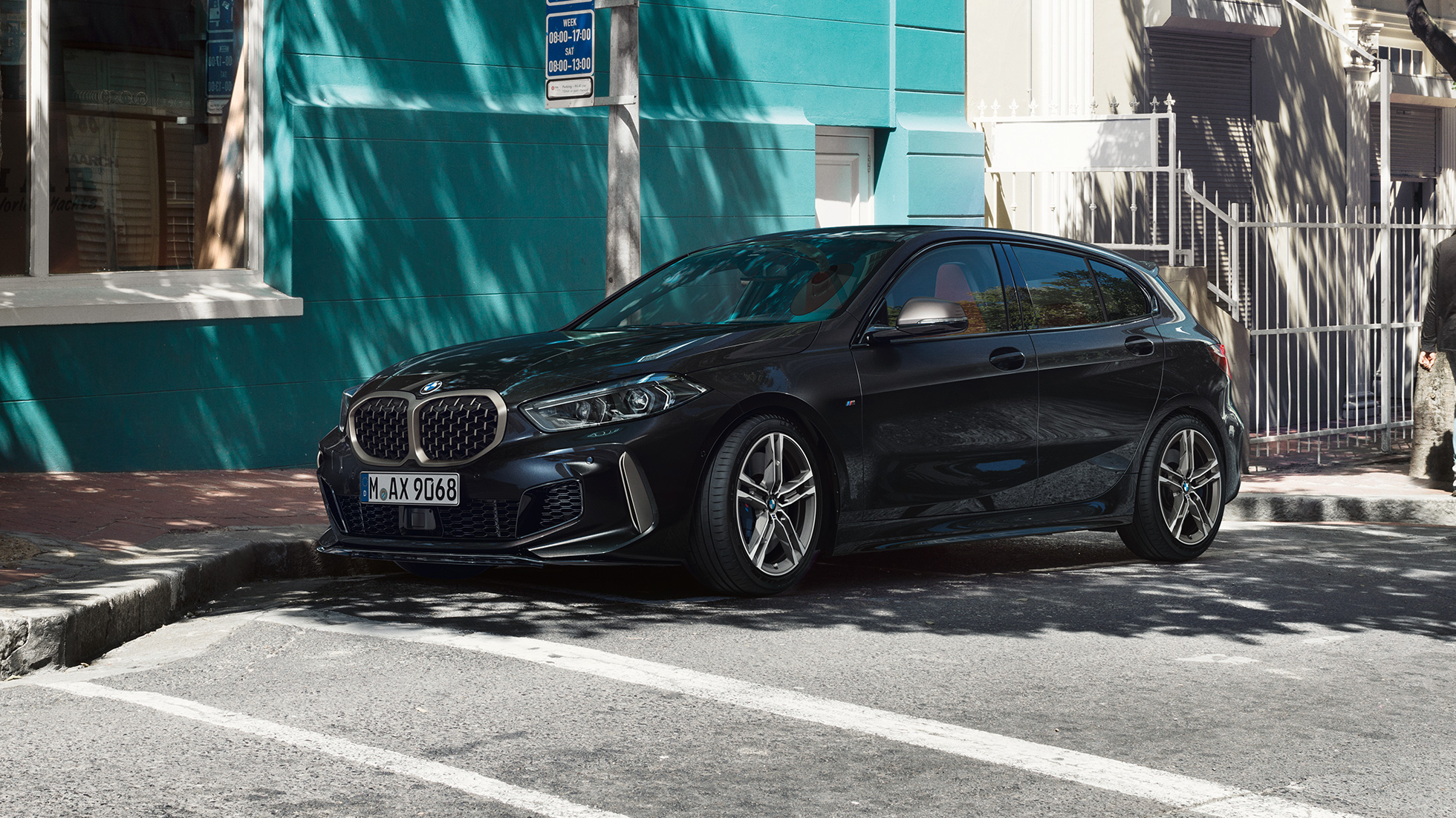 BMW M135i xDrive noire à l'arrêt dans une rue à l'ombre BMW M135i xDrive noire à l'arrêt dans une rue à l'ombre