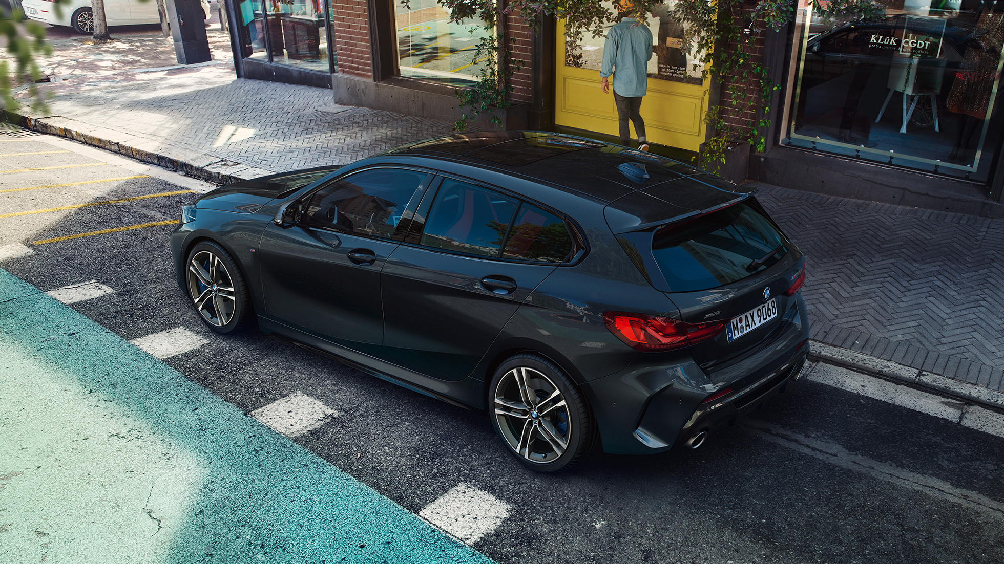 BMW M135i xDrive, en stationnement F40. BMW M135i xDrive en Saphirschwarz metallic, vue de trois quarts de profil en plongée, en stationnement F40.