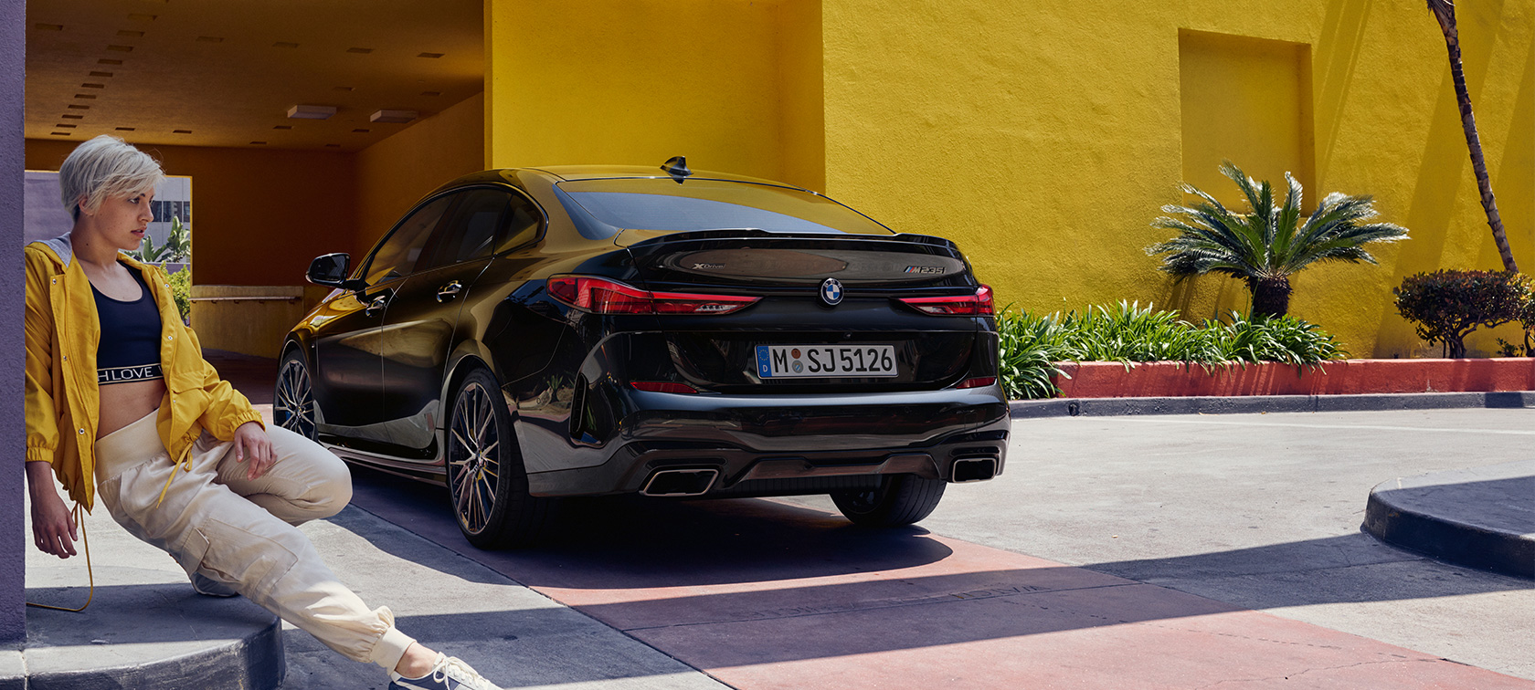 BMW M235i xDrive Gran Coupé, vue de trois quarts arrière F44 BMW M235i xDrive Gran Coupé Black Sapphire metallic F44, vue de trois quarts arrière avec femme au premier plan
