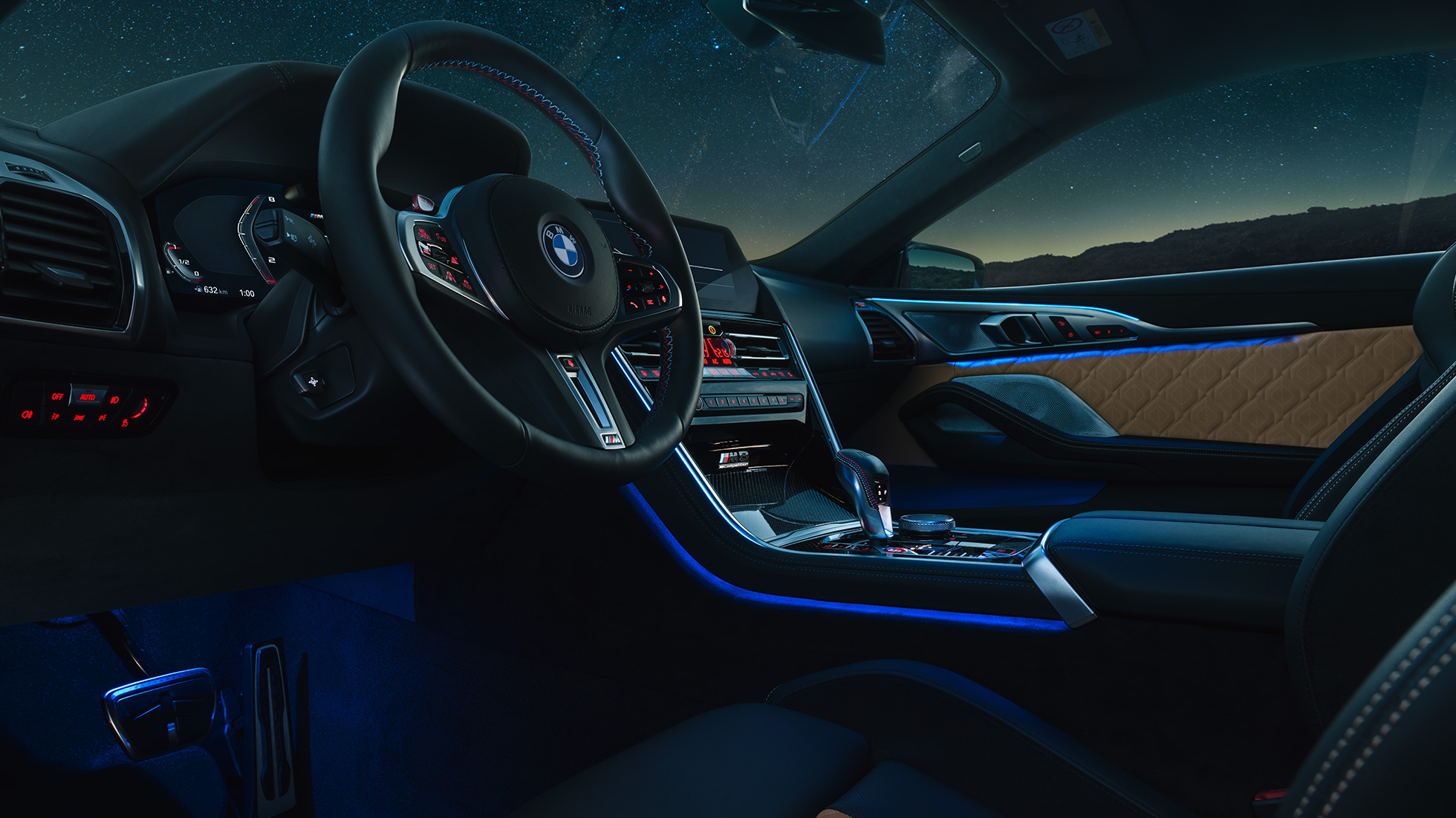 BMW M8 Competition Coupé, poste de conduite F92. BMW M8 Competition Coupé, prise de vue nocturne du poste de conduite avec volant M en cuir et éclairage d’ambiance bleu F92.