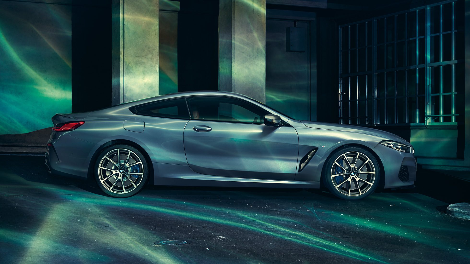 BMW M850i xDrive Coupé, vue de profil G15. BMW M850i xDrive Coupé en Barcelona Blau metallic, vue de profil, à l’arrêt devant un immeuble G15.