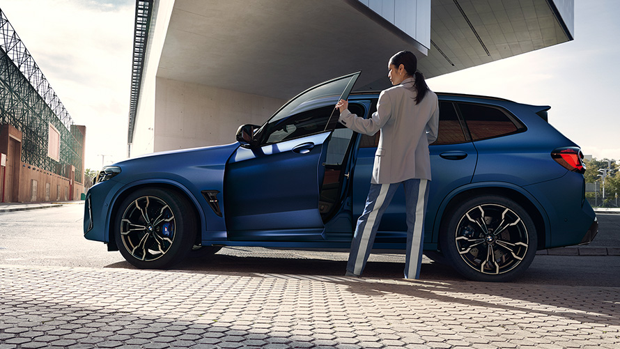 BMW X3 M Competition F97 LCI restylage 2021 Frozen Marina Bay Blau metallic Vue de profil avec portière ouverte et mannequin femme