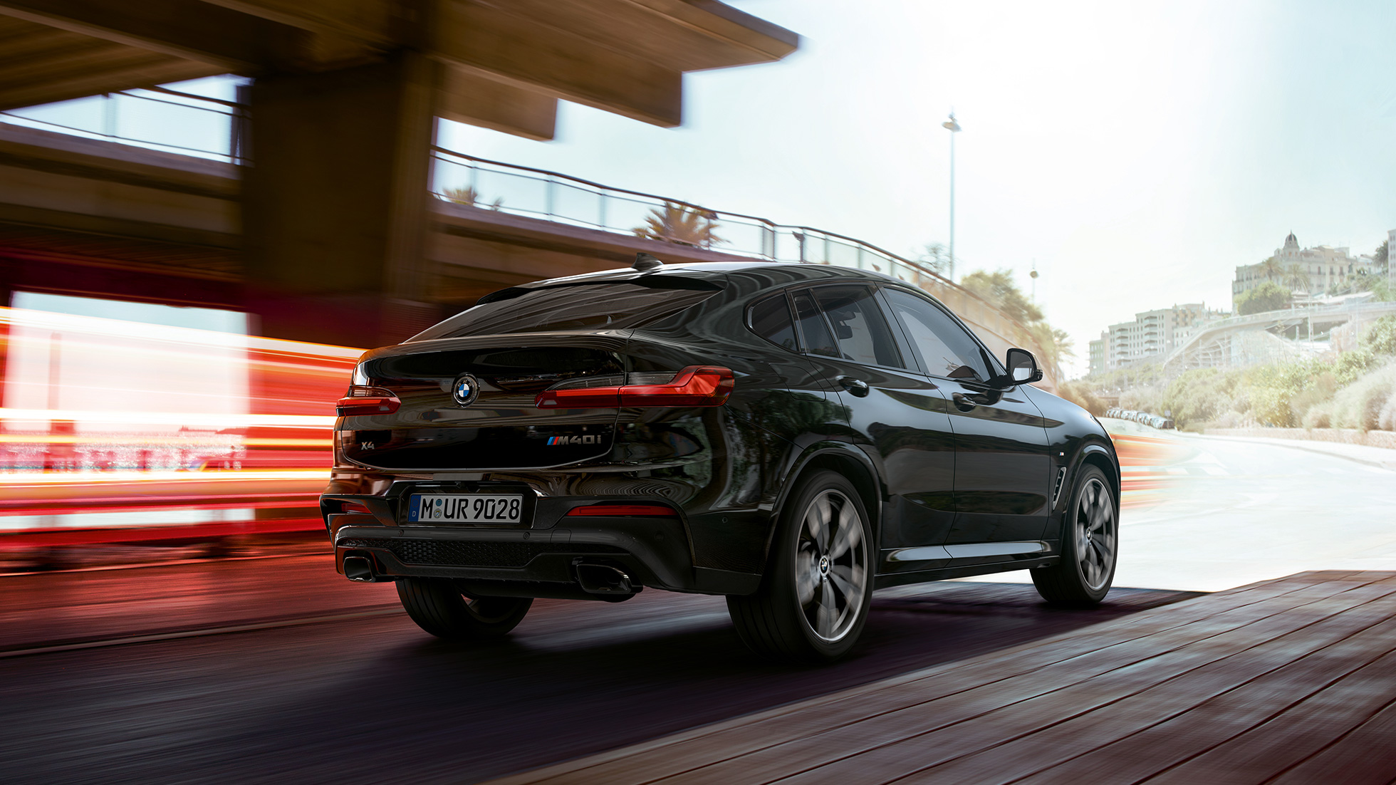BMW X4 M40i, vue de trois quarts avant G02. Extérieur de la BMW X4 M40i en Saphierschwarz metallic, en mouvement, vue de trois quarts avant avec bandes lumineuses G02.