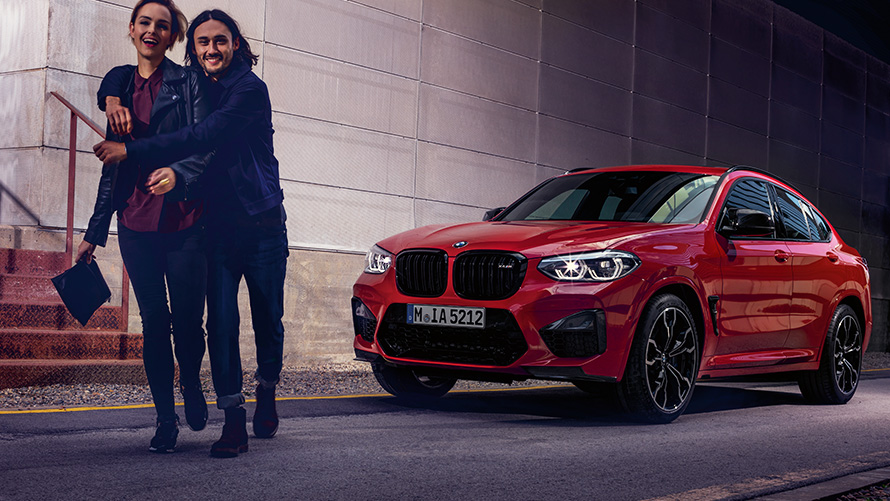 BMW X4 M rouge de trois quart face BMW X4 M rouge de trois quart face avec des figurants