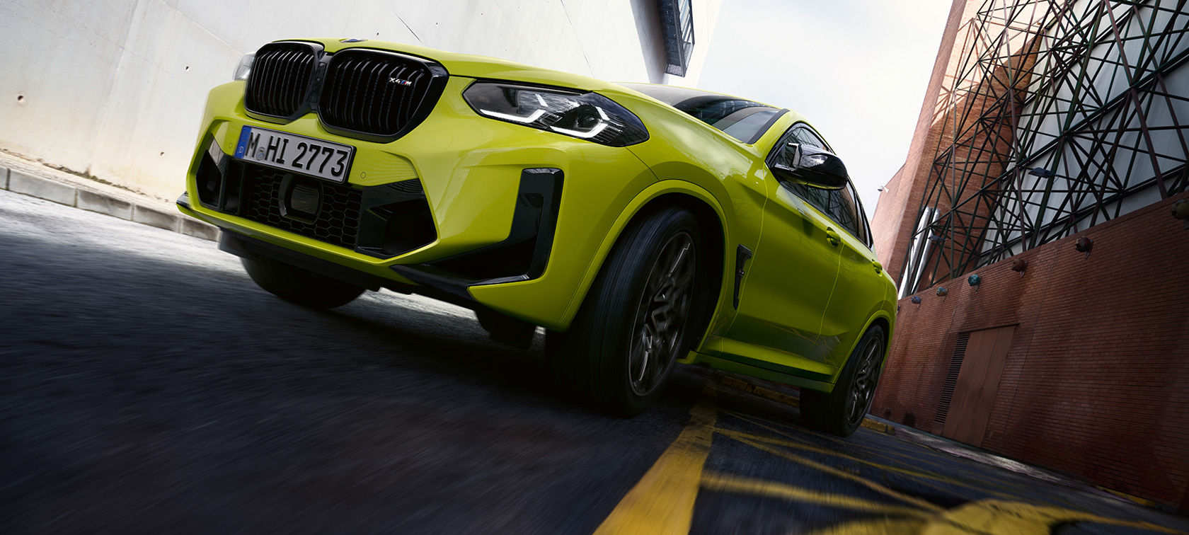 BMW X4 M Competition F98 LCI Facelift 2021 Sao Paulo Gelb vue de trois quarts face avec contre-plongée en mouvement dans un canyon urbain
