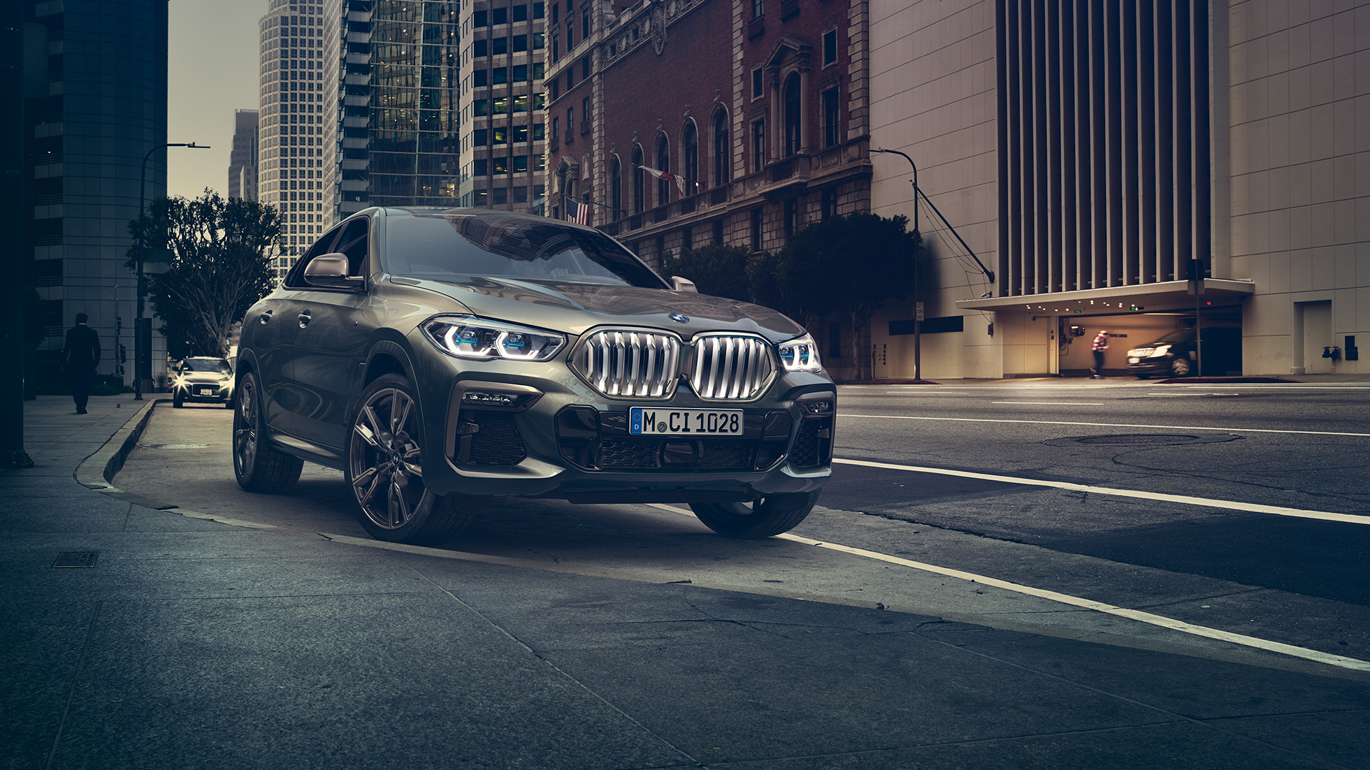 BMW X6 M50i à l’arrêt BMW X6 M50i vue de trois quarts face à l’arrêt devant un décor urbain
