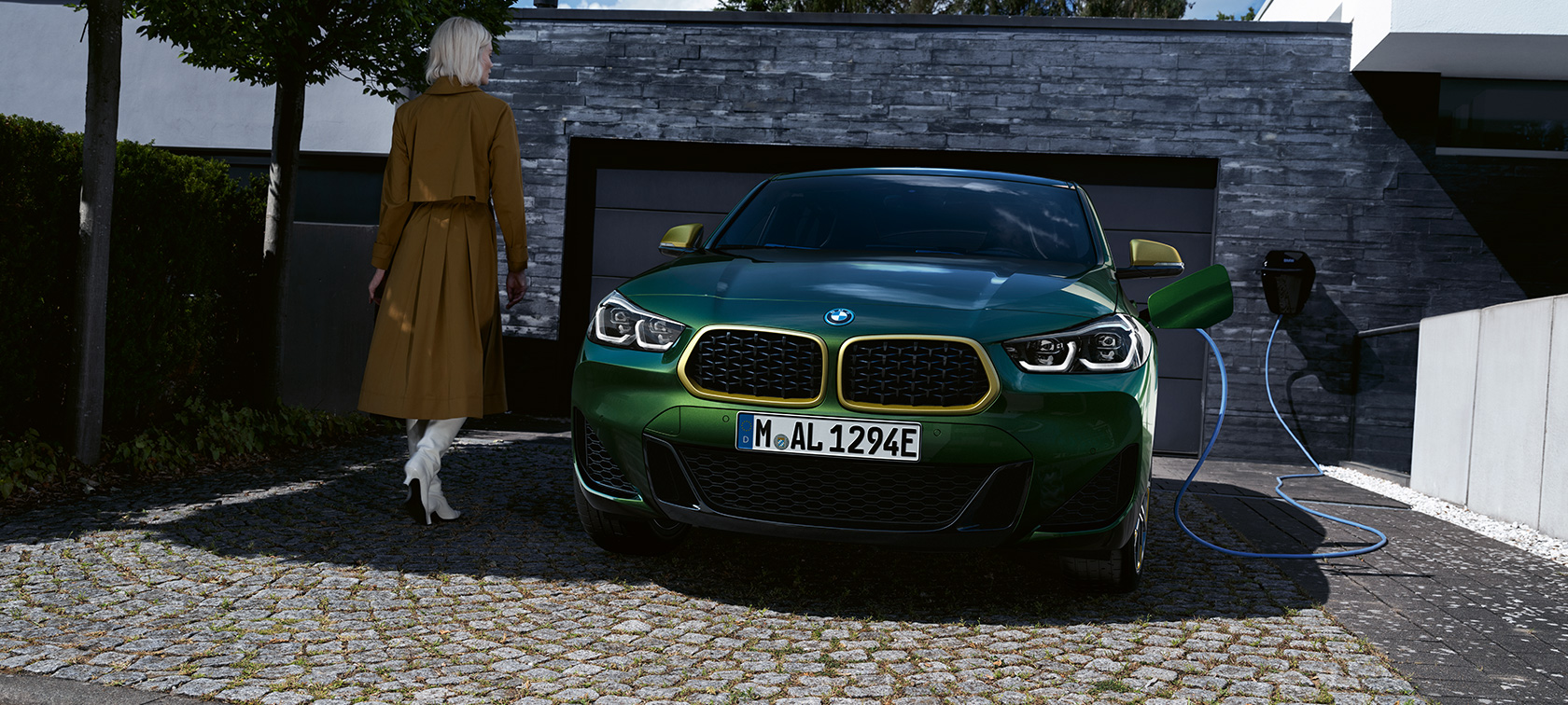 SUV hybride BMW X2 F39 Sanremo Green métallisé, en recharge, vue de trois quarts arrière avec modèle