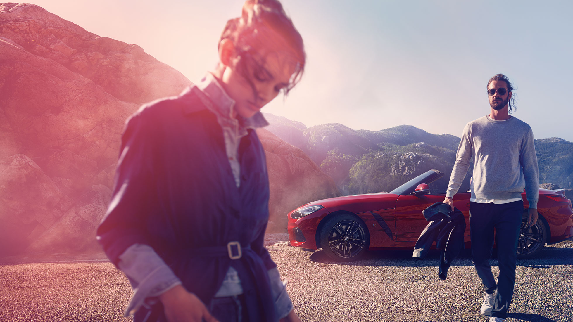La BMW Z4 Roadster devant un paysage de montagnes G29 Homme et femme devant la BMW Z4 Roadster avec à l’arrière-plan un paysage de montagnes G29
