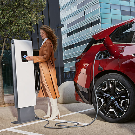 BMW iX i20 sur une borne de recharge, femme avec BMW Charging Card