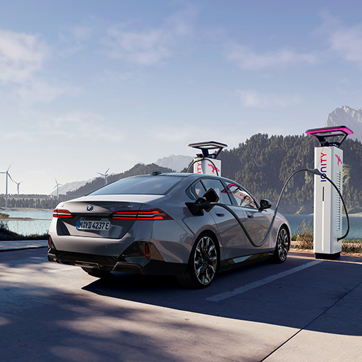 BMW i5 eDrive40 G60 sur une borne de recharge devant un lac