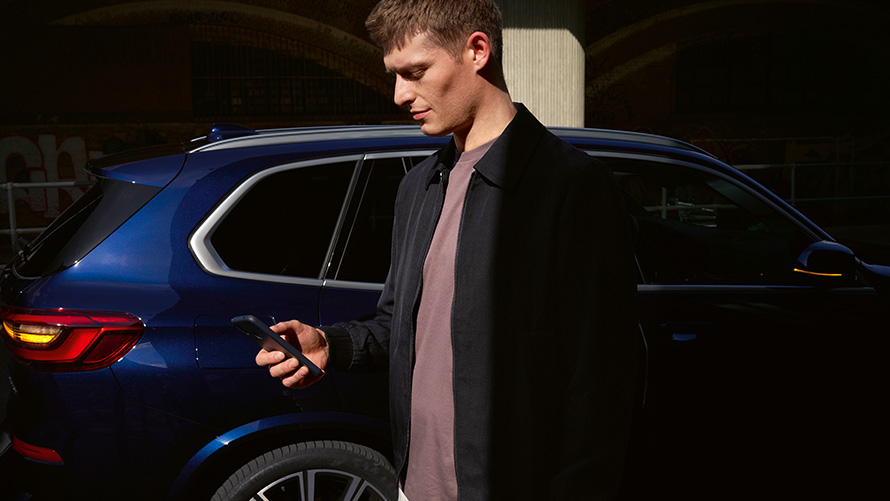 BMW Digital Key – configurer jusqu'à cinq utilisateurs BMW Digital Key configuration de jusqu'à cinq utilisateurs homme avec smartphone devant BMW X5