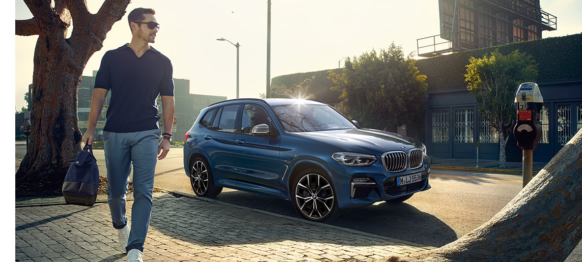 Homme avec des lunettes devant une BMW bleue Homme avec des lunettes devant une BMW bleue