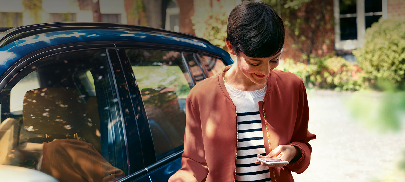 BMW Teleservices Femme regarde son smartphone BMW Teleservices Femme devant BMW regarde son smartphone