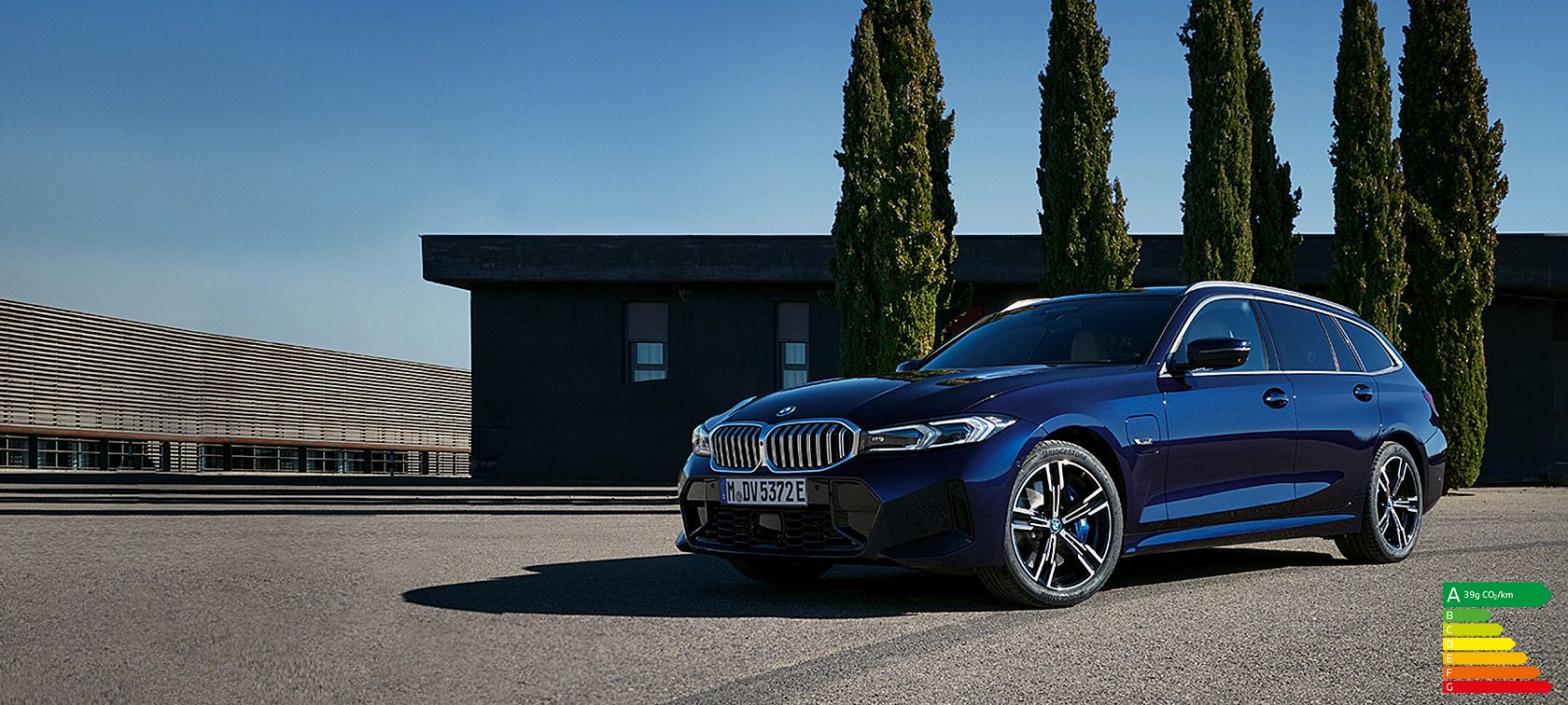 BMW Série 3 Touring LCI G21 Tansanitblau II vue de trois quarts avant à l’arrêt devant des arbres