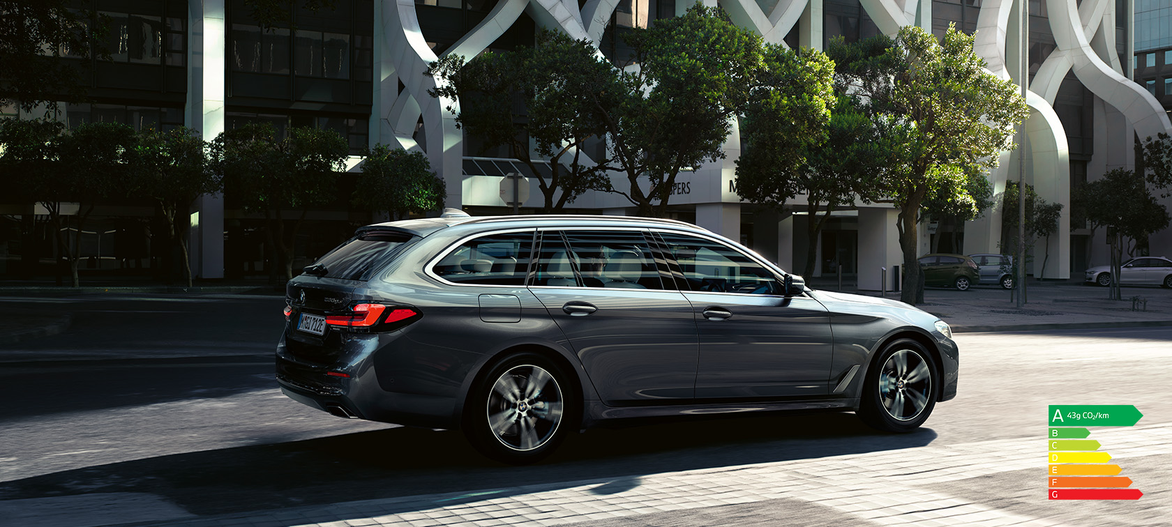 BMW 530e Touring G31 LCI en Sophistograu metallic, à l’arrêt devant des bâtiments