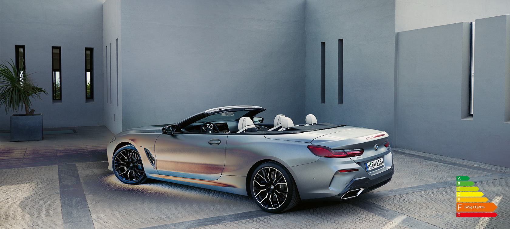 BMW 8 Series Convertible G14 LCI Facelift 2022 BMW Individual Frozen Pure Grey metallic side view with open softtop driving along mountain wall