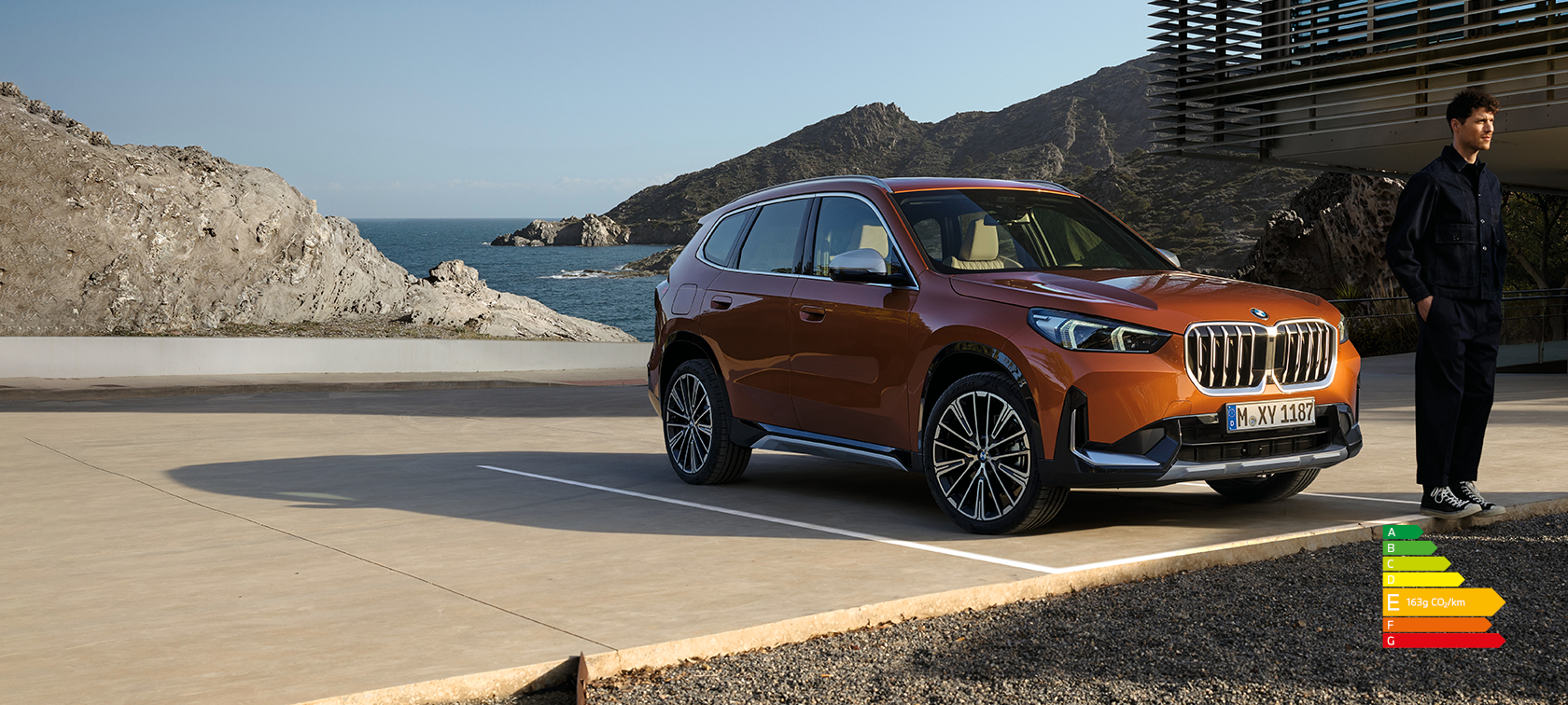 BMW X1 U11 xLine Utah orange metallic, vue de trois quarts avant sur route de campagne