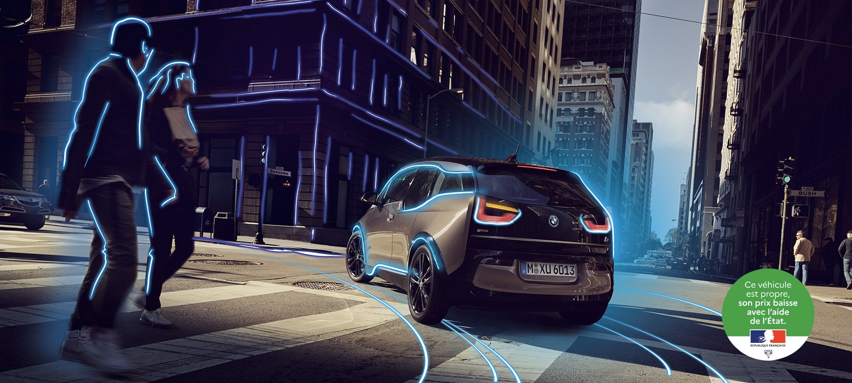 Les offres électriques. BMW i3 (I01) Jucaro Beige avec Gris Glacé accent trois quarts vue d'arrière conduite dans la ville