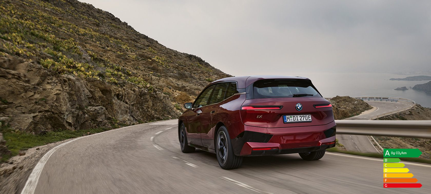 BMW iX i20 2021 SUV électrique BMW iX xDrive50 Aventurinrot vue arrière en roulant sur une route côtière