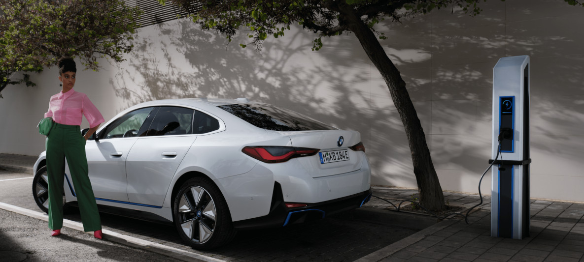 Photo d’une femme rechargeant sa voiture électrique sur une borne