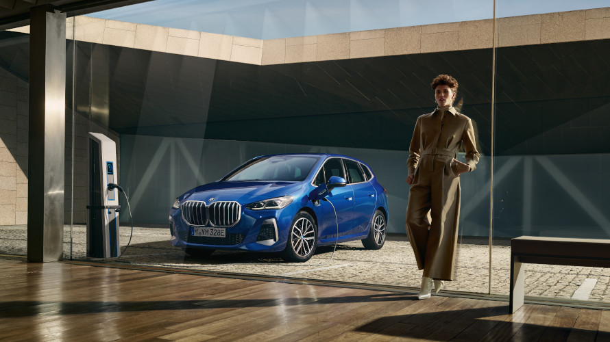 Femme à côté d'une voiture hybride rechargeable bleue