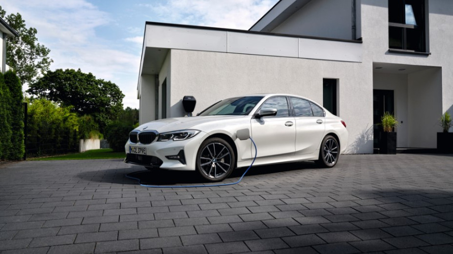 BMW Série 3 Berline Hybride Rechargeable d'occasion, blanche, garée et branchée à une borne de recharge