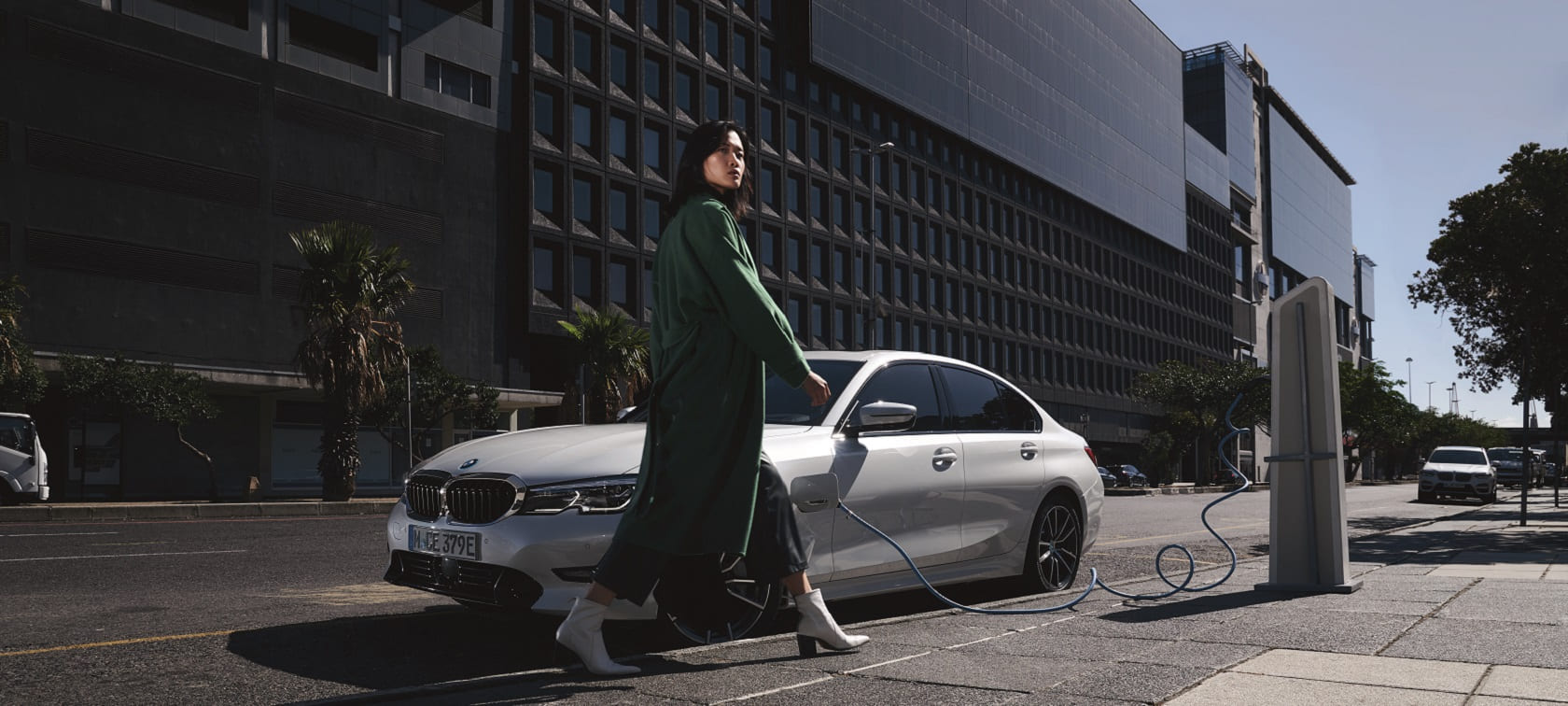 BMW Série 3 Berline d'occasion, blanche, garée et branchée à une borne de recharge