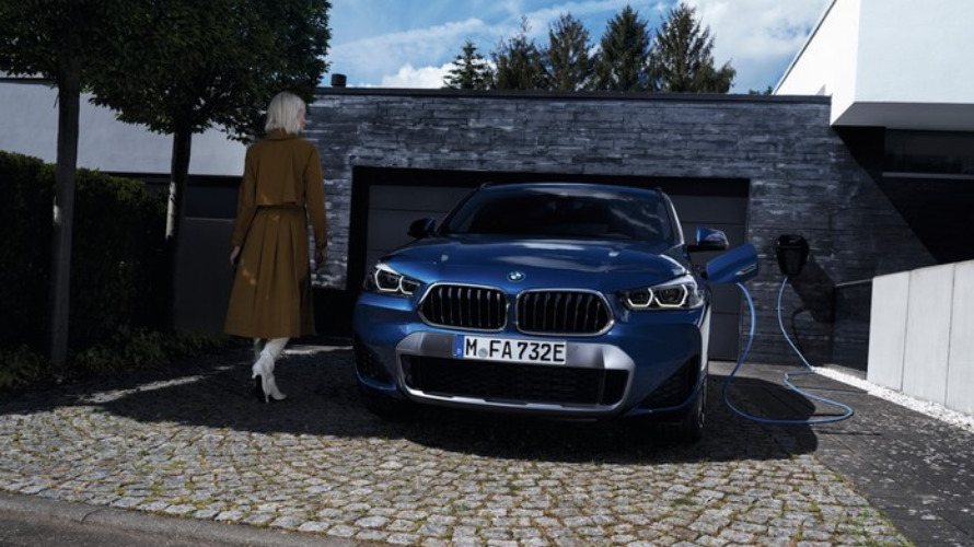 BMW X2 d'occasion Hybride Rechargeable, SUV Compact, vue de face, borne de recharge, stationnée