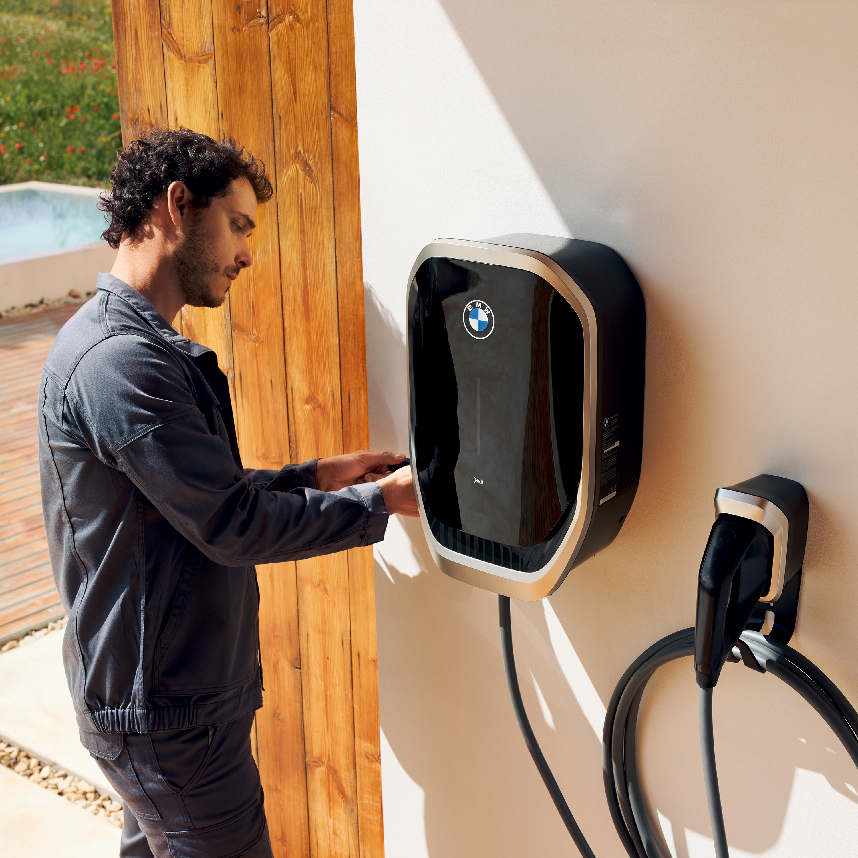 Une personne branche un câble de recharge sur une wallbox BMW